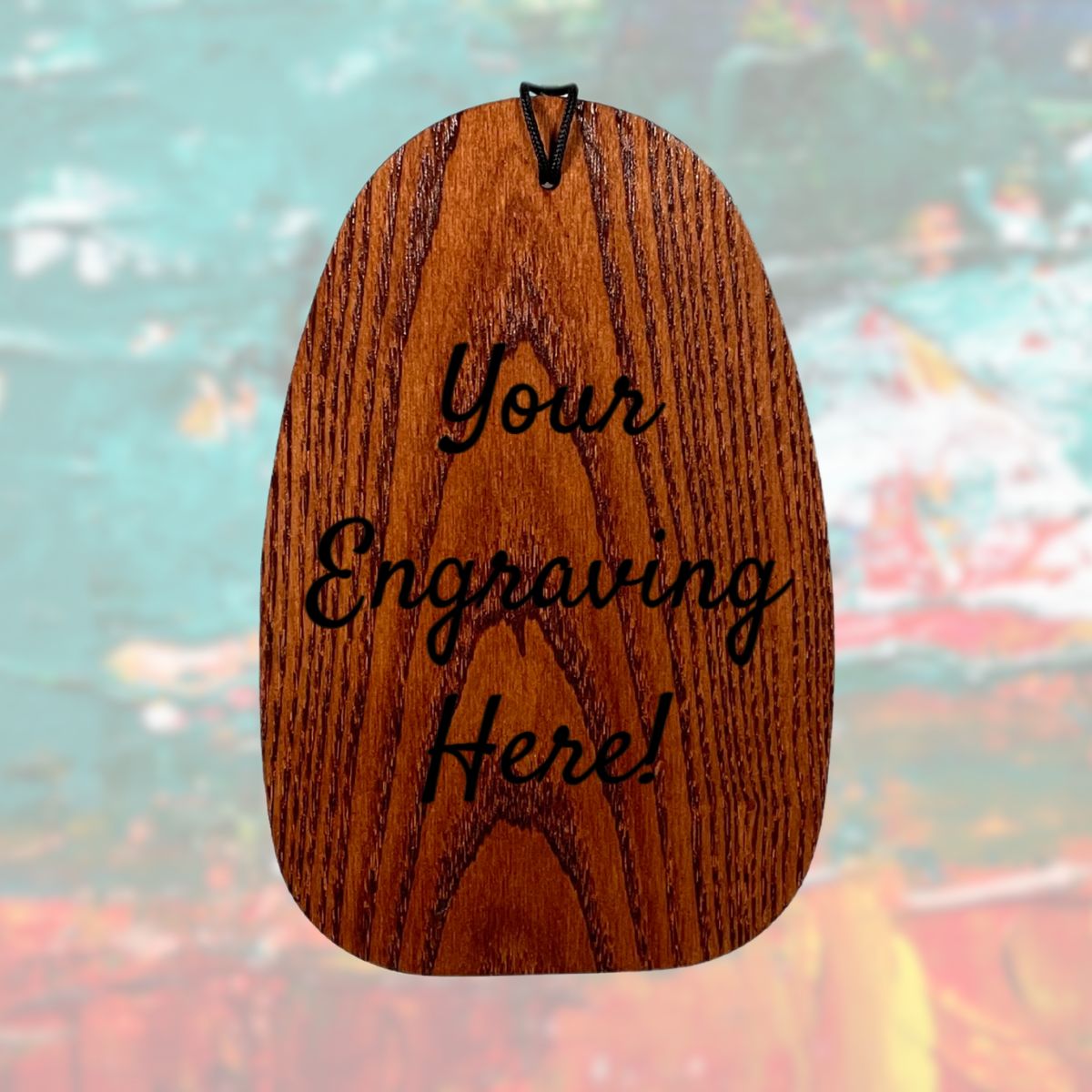 Wooden wind sail with 'Your Engraving Here!' text engraved and a colorful blurred background