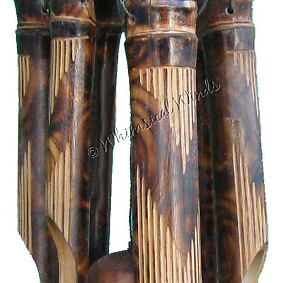 A close up of a V-shape burnt design on the tubes of a bamboo wind chime against a white background