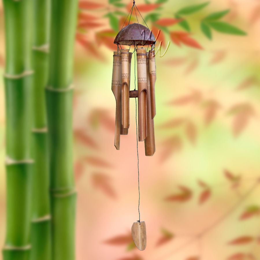 Bamboo wind chime with a lace pattern on the tubes and a coconut top against a blurred natural bamboo background