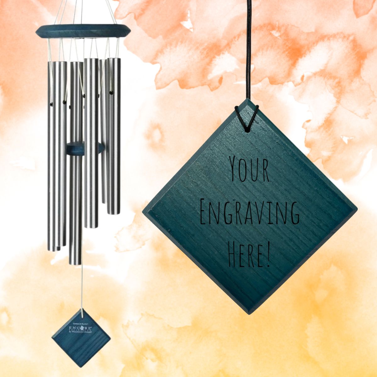 Woodstock brand 'Chimes of the Eclipse' silver aluminum tubes wind chime that is 27 inches in length, with customizable blue stained wooden wind sail, shown with placeholder text 'Your Engraving Here!' displayed in front of a watercolor background