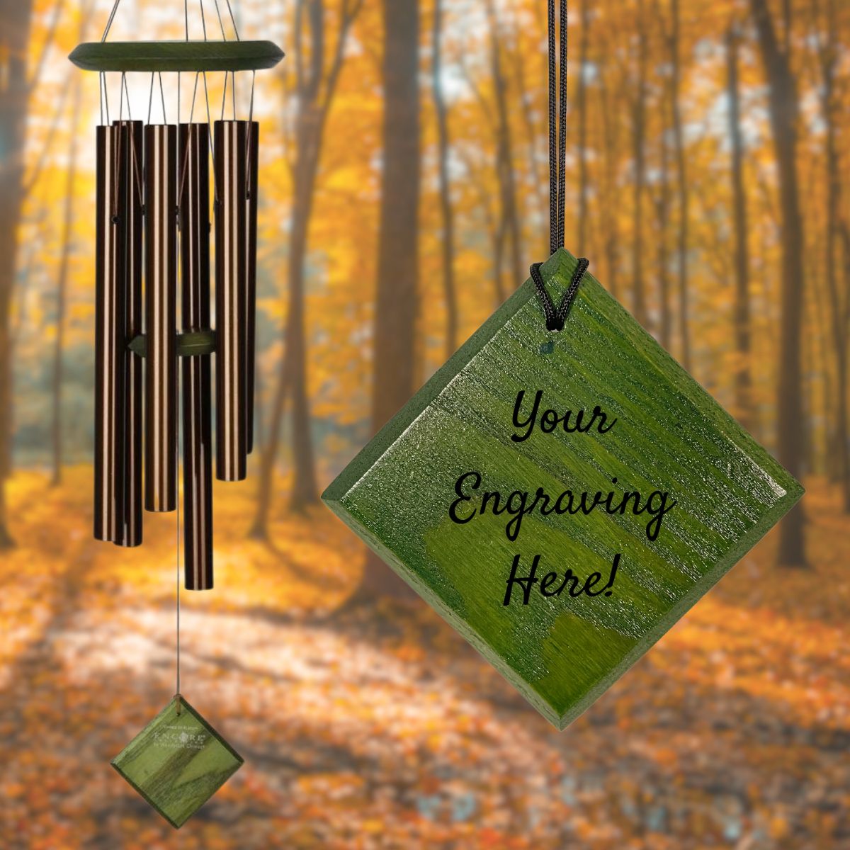 Woodstock brand 'Chimes of the Eclipse' bronze aluminum tubes wind chime that is 27 inches in length, with customizable green wooden wind sail, shown with placeholder text 'Your Engraving Here!' displayed in front of a landscape background