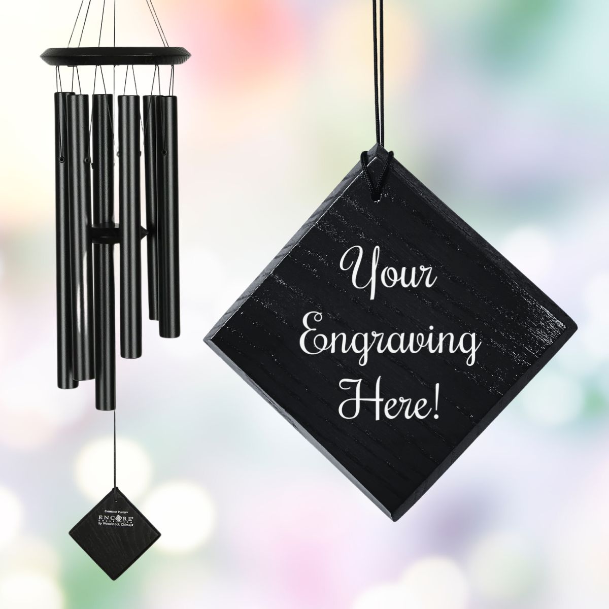 Woodstock brand 'Chimes of the Eclipse' black aluminum tubes wind chime that is 27 inches in length, with customizable black stained wooden wind sail, shown with placeholder text 'Your Engraving Here!' displayed in front of a watercolor background