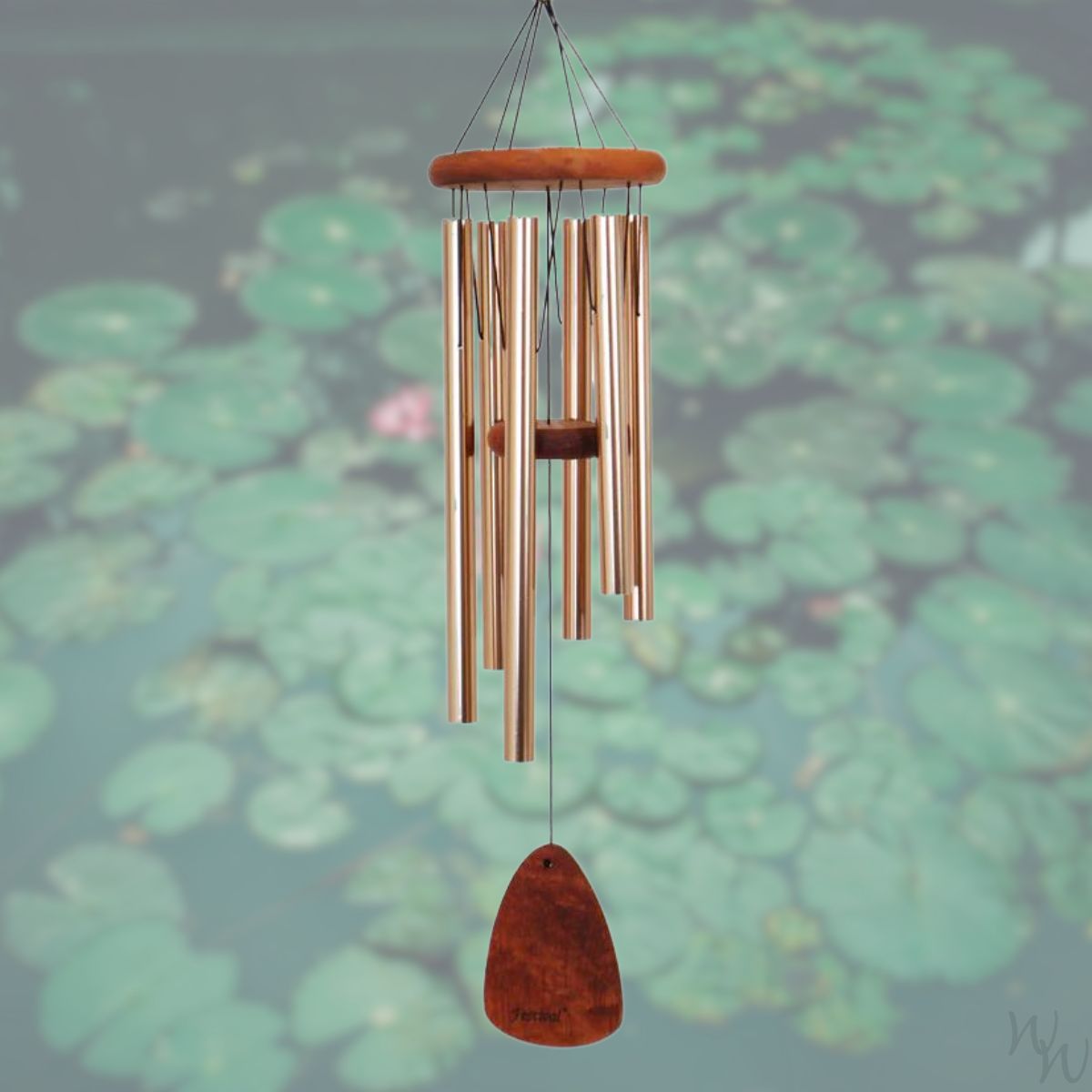 Festival 30 inch bronze wind chime with wooden striker and wind sail,  against a blurred natural background