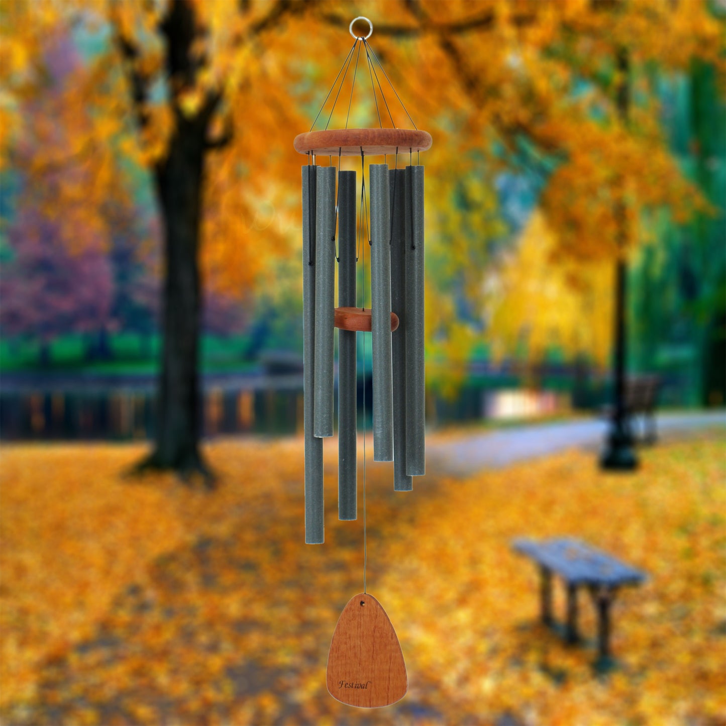 Festival 36 inch forest green wind chime with wooden striker and wind sail, wind chime with wooden accents against a blurred autumn park background