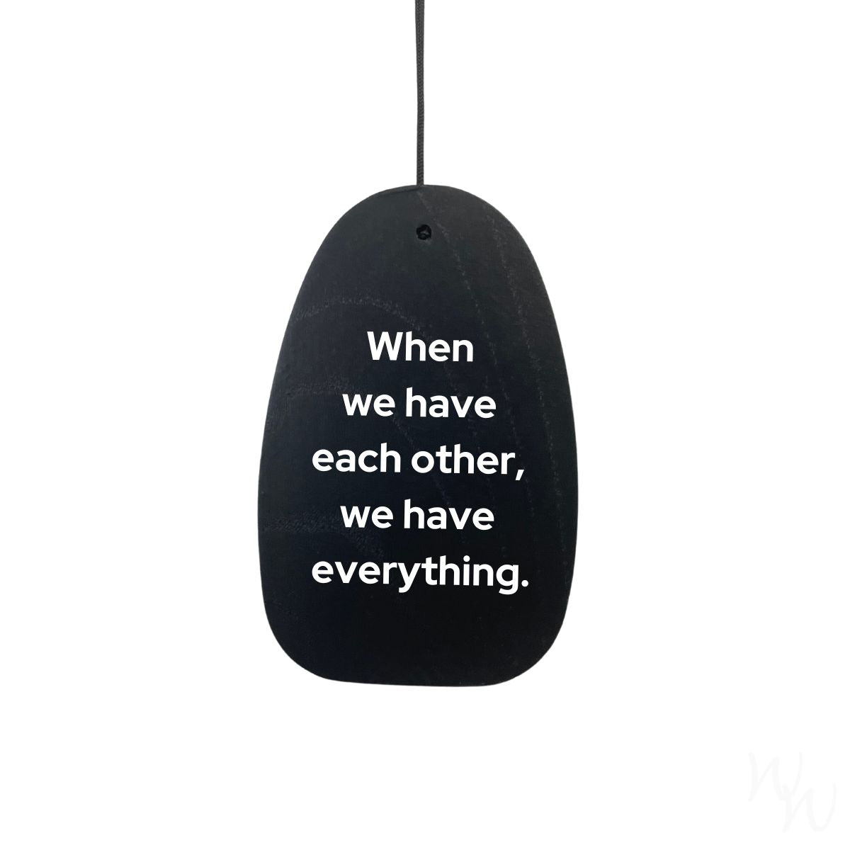 Black wooden wind sail with white text on the wind sail that reads "When we have each other, we have everything." used as an example engraving.
