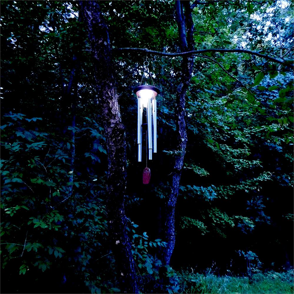 Woodstock Chimes Moonlight Solar Chime in silver finish, featuring the solar-powered LED light softly glowing in the evening