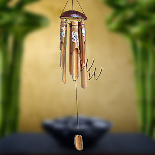 Bamboo wind chime with a half coconut as the top and butterflies painted on the tubes, blurred greenery in the background
