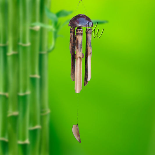 Bamboo wind chime with a half coconut as the top and a V-shape design on the tubes hanging against a green bamboo background