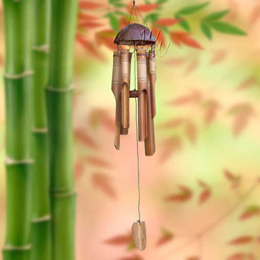Bamboo wind chime with a lace pattern on the tubes and a coconut top against a blurred natural bamboo background