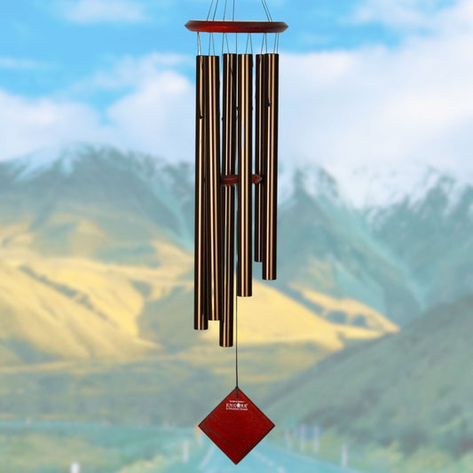 Woodstock brand 'Chimes of the Eclipse' bronze aluminum tubes wind chime that is 37 inches in length, with customizable red wooden wind sail displayed in front of a landscape background 