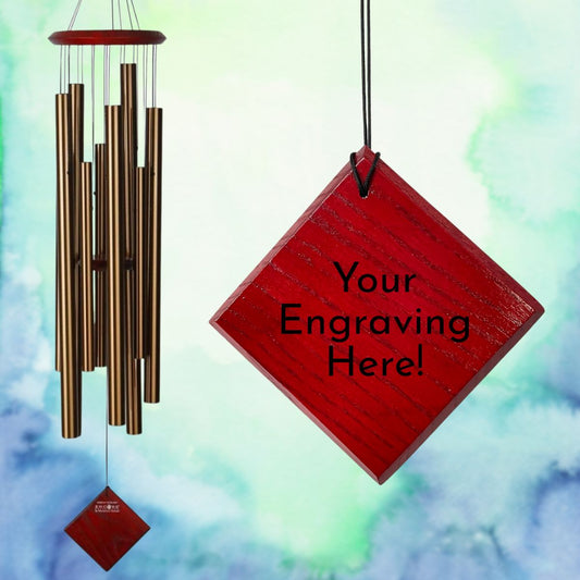 Encore 40 inch Chimes of the Eclipse with bronze tubes and a red diamond-shaped wind sail, with a close up of an engraved example wind sail that reads "Your Engraving Here!" against a blurred abstract blue and green watercolor background