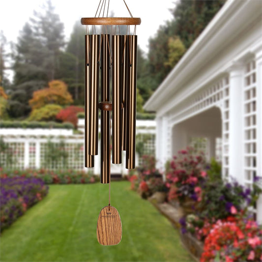 Woodstock brand 'Amazing Grace' wind chime with bronze aluminum tubes that is 25 inches in length, and customizable bronze wooden wind sail displayed in front of a nature landscape background