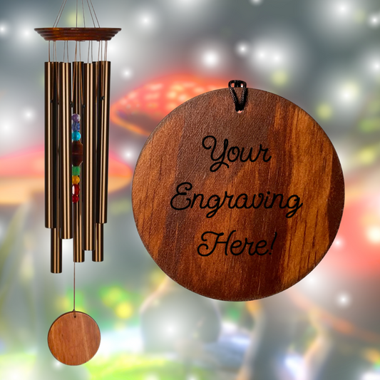Woodstock Percussion 7‑Stone Bronze Chakra Wind Chime with engravable wooden wind sail WITH seven bronze aluminum tubes hang from teak‑finish ash‑wood top; the faceted clapper aligns seven chakra stones vertically, with a round wooden sail below that can be personalized with up to 50 characters